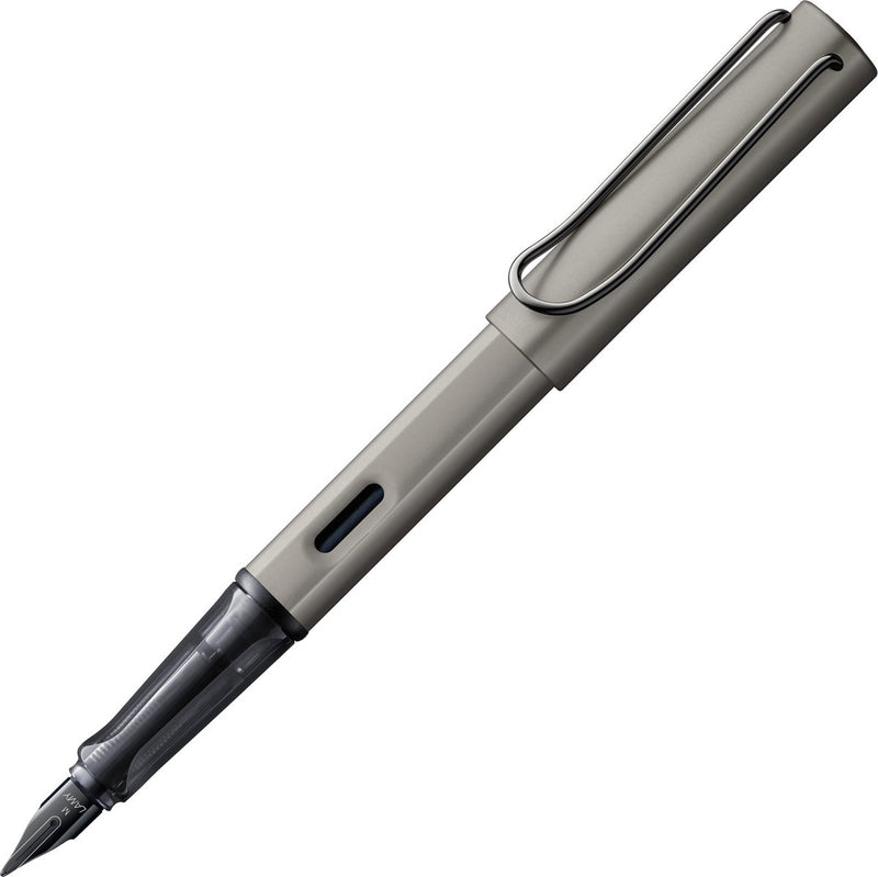 Pluma estilográfica de lujo Lamy lx 057 de aluminio claro en color rutenio con acabado de metales preciosos y plumín de acero PVD negro brillante, incluye cartucho de tinta T 10 en azul y paquete de regalo.
